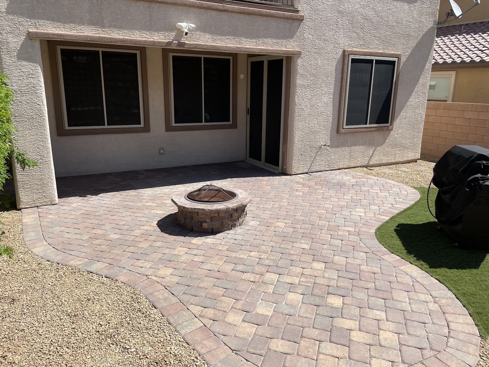 Clean paver patio with a fire pit in a home backyard
