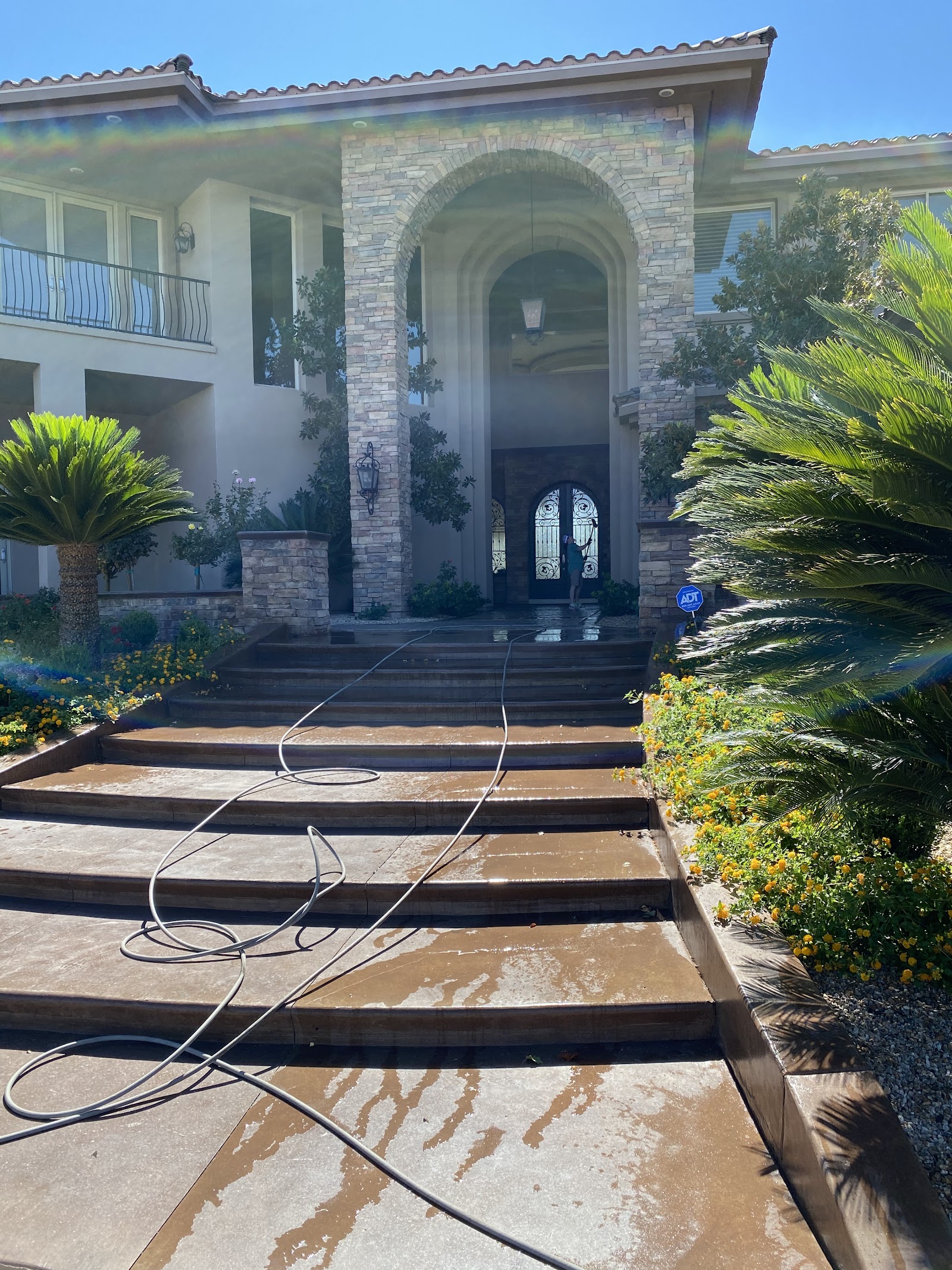 Large stone-facade home entrance with wet steps being pressure washed
